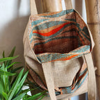 Sac cabas en toile de jute avec un gros nœud en tissu wax orange bleu et beige sur le devant et intérieur tout en wax
