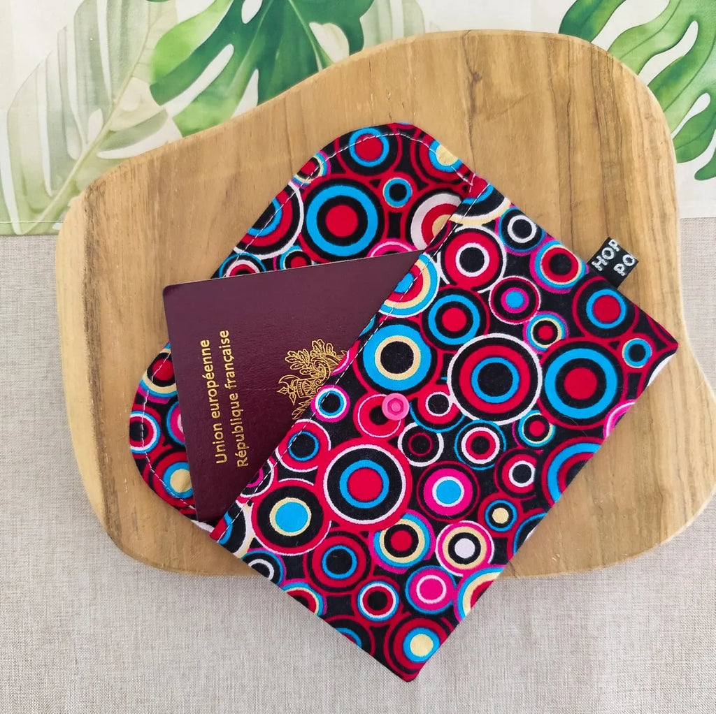 mini pochette format enveloppe en tissu wax motif cercles bleu rose et rouge ouverte avec passeport