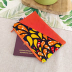 Mini pochette zippée en suédine orange et tissu wax motif pétales ouverte avec passeport rangé