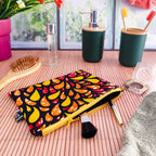 Pochette plate molletonnée en tissu wax fait main motifs orange rouge et jaune dans salle de bain