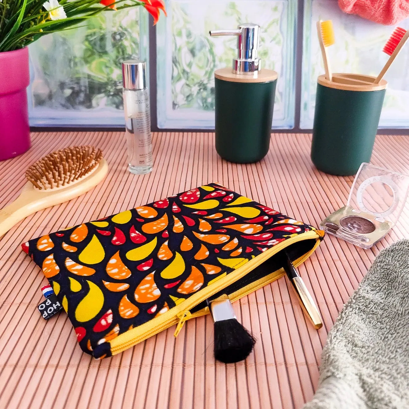 Pochette plate molletonnée en tissu wax fait main motifs orange rouge et jaune dans salle de bain