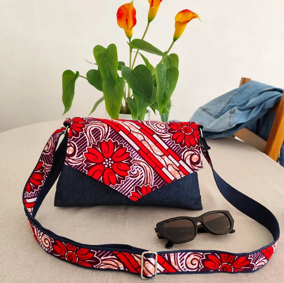 Sac à main en tissu jean denim bleu marine et tissu wax rouge et blanc sur une table