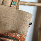 Sac cabas en toile de jute avec un gros nœud en tissu wax orange bleu et beige sur le devant vue du haut du sac